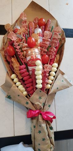 a bouquet of food wrapped in brown paper on a tiled floor next to a towel