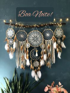 a wall hanging with dream catchers and lights on it's side next to a potted plant