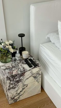 a marble box with candles and flowers on it next to a bed in a bedroom