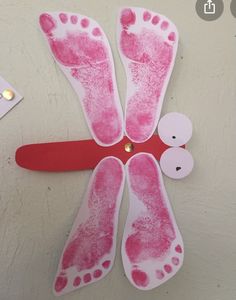 a paper plate with pink footprints on it next to some scissors and other crafting supplies