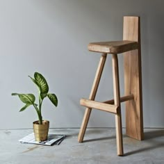 a wooden stool next to a potted plant