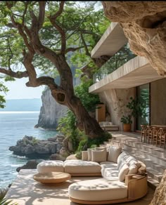 an outdoor living area with couches and tables next to the ocean