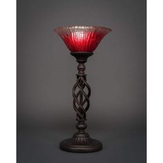 a red glass vase sitting on top of a wooden stand