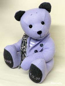 a purple teddy bear sitting on top of a white table