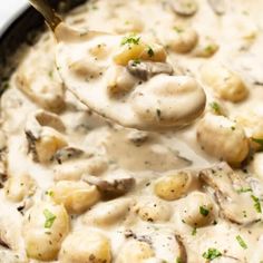 a ladle scooping some food out of a pot filled with mushroom and broccoli gravy