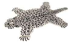 a white and black animal rug with spots on it's back legs, in the shape of a cheetah