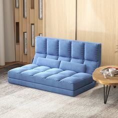 a living room with a blue couch and coffee table next to it on carpeted flooring