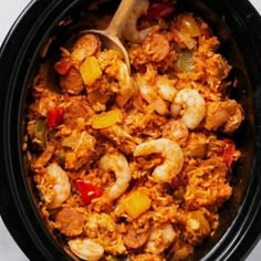 a bowl filled with rice and shrimp next to a wooden spoon