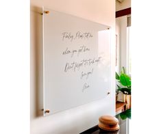 a white board with writing on it in a room next to a vase and potted plant