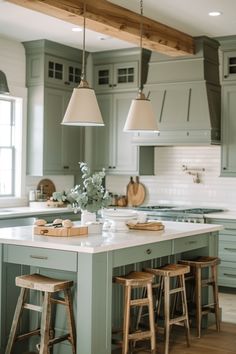 a kitchen island with stools in front of it and lights hanging from the ceiling