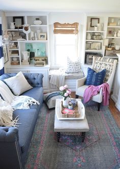 a living room filled with furniture and lots of shelves on the wall next to a window