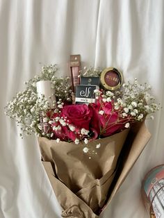 a bouquet of flowers and cosmetics on a white sheet