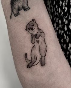 a small tattoo on the arm of a woman with an animal in it's arms