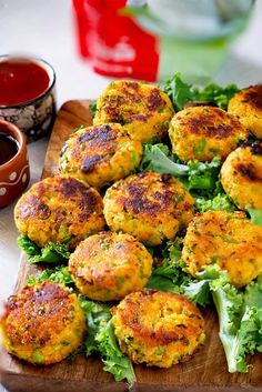 some crab cakes are on a cutting board with lettuce and sauces next to it