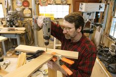 a man is working on woodworking in his shop with a power drill and tools