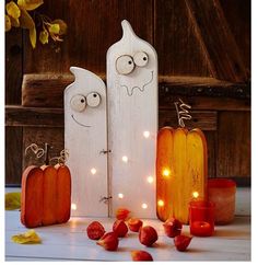 two wooden pumpkins with faces on them next to candles