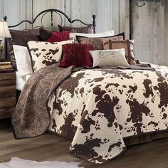 a bed covered in brown and white cow print comforter with pillows on top of it