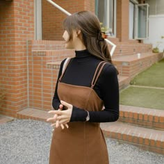 a woman standing in front of a brick building with her hands out to the side