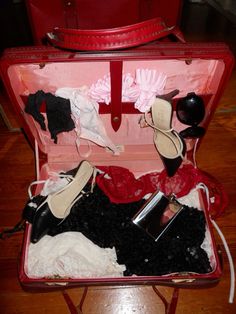 an open red suitcase filled with clothes and shoes on top of a hard wood floor