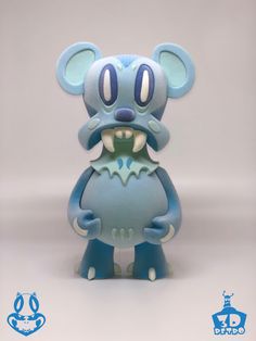 a blue and white figurine with big teeth on it's face, standing in front of a gray background