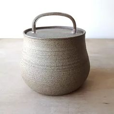 a stone pot sitting on top of a wooden table next to a brown handled handle