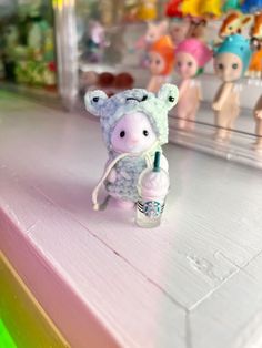 a small stuffed animal sitting on top of a pink counter next to other toy figurines