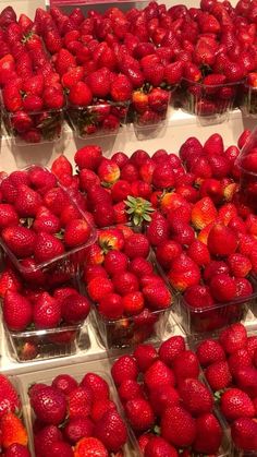 strawberries are arranged in plastic containers on display