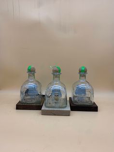 three glass bottles sitting on top of a wooden base