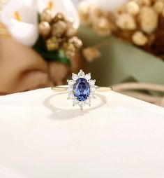 a blue and white diamond ring sitting on top of a table next to some flowers