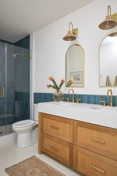 a bathroom with blue tile and gold fixtures on the vanity, toilet and shower stall