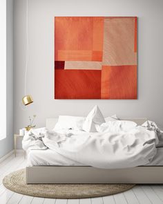 an orange painting hangs above a bed with white sheets