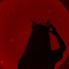 the silhouette of a woman with a crown on her head in front of a red background