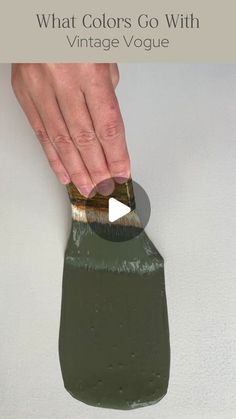 a person is using a paint brush to paint a green vase with white and brown colors