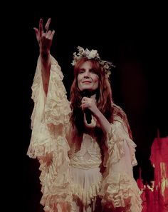 a woman in a white dress holding her hands up