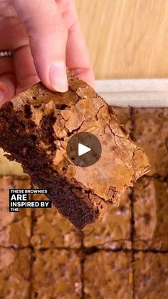 a person is holding a piece of brownie in their hand and it looks like they are eating something