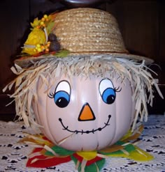 a pumpkin with a scarecrow hat on it's head sitting on a table