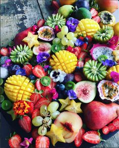 an assortment of fruits and vegetables on a plate with fruit in the middle, including bananas, strawberries, kiwis, peaches