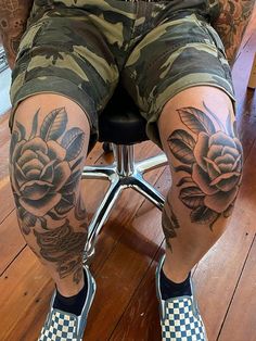 a man sitting on top of a chair with his legs covered in tattoos and flowers