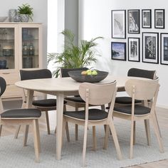 a dining room table and chairs with pictures on the wall