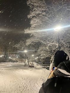 a person standing in the snow at night with their back turned to the camera,