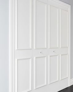 an empty room with white closet doors and black flooring in the center, along with hardwood floors