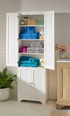 a bathroom with white shutters and towels on the shelves