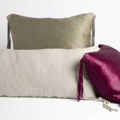 a white pillow with purple tassels on it next to a gray and white pillow