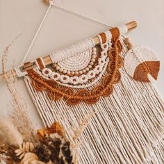 the wall hanging is decorated with white and brown beads, tassels and wood beads