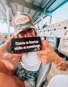 a woman sitting in a stadium holding up a cell phone