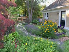 a garden with lots of flowers next to a house