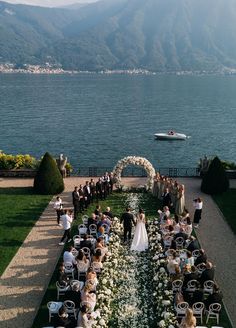 an outdoor ceremony on the water with people sitting at tables and looking out over the water