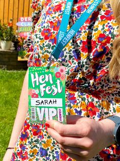 a woman in a colorful dress holding up her name tag for the hen fest event