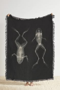 a black and white photo of two bugs on a blanket with fringes hanging from it