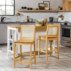 two wooden chairs sitting in front of a counter top next to a stove and oven